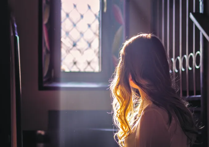 Jeune adolescente regardant par la vitre d'une église. © iStock